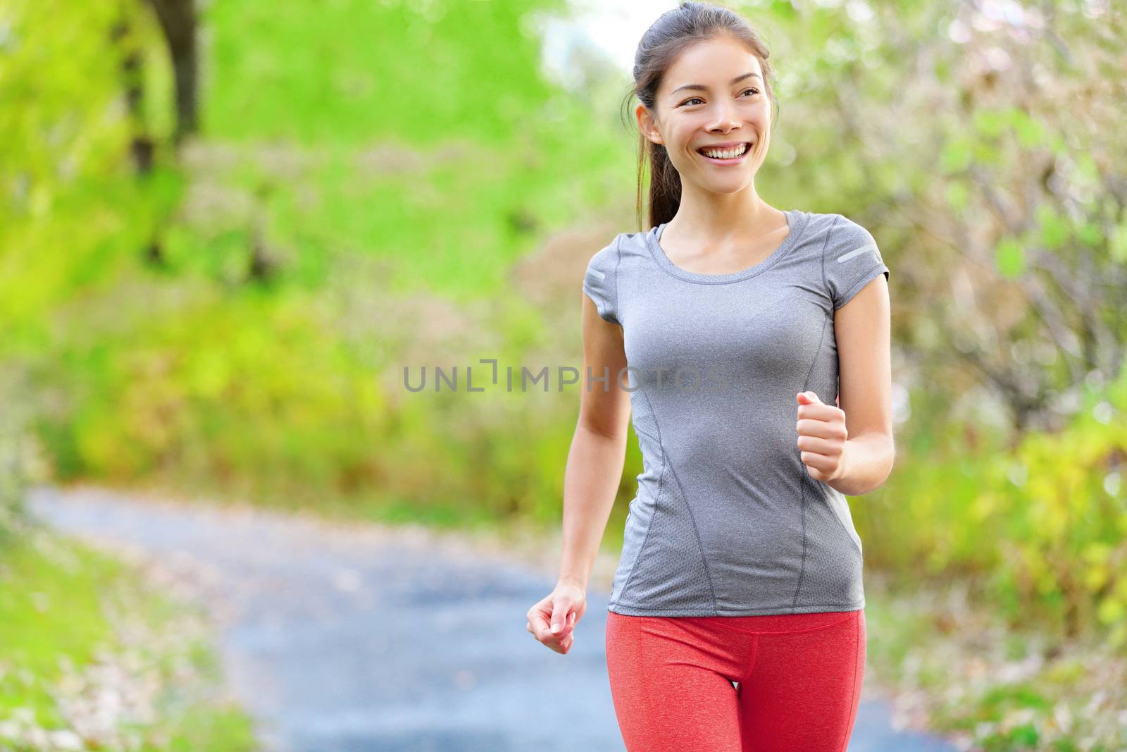 Woman nordic speed power walking, jogging and running lightly in forest in spring or summer. Sport fitness girl sports training and working out living healthy active lifestyle in forest.