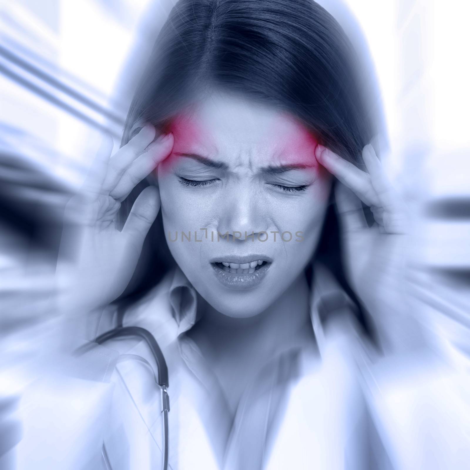 Young woman with a pounding headache or migraine standing clutching her temples with an expression of pain, monochrome image with selective red color to temples and blur effect around her face