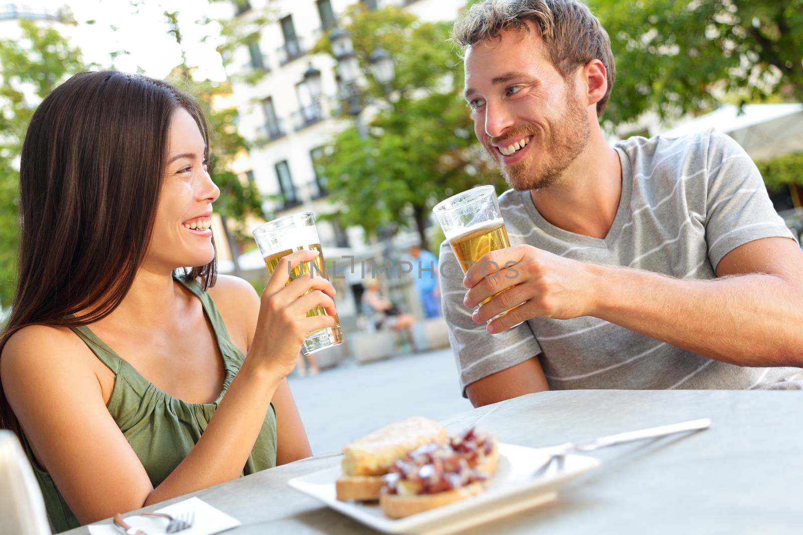 Couple eating tapas drinking beer in Madrid Spain by Maridav