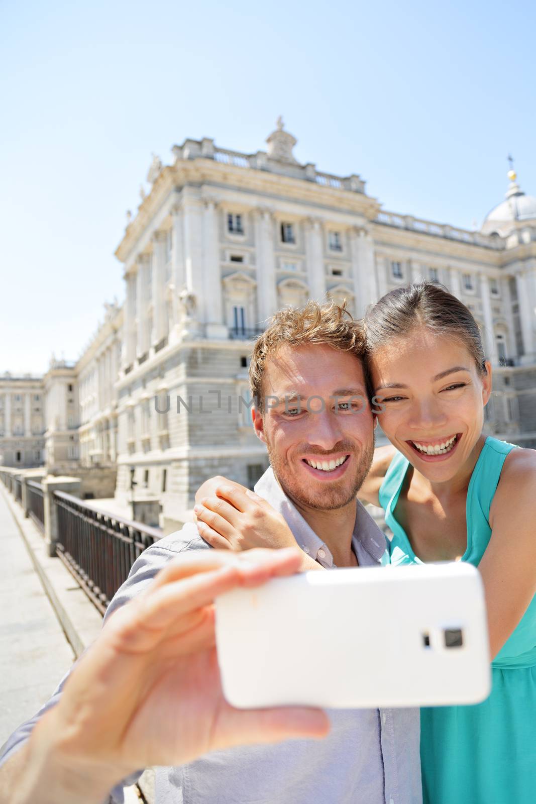 Couple taking selfie photo on smartphone in Madrid. Romantic man and woman in love using smart phone to take self-portrait photograph on travel in Madrid, Spain.