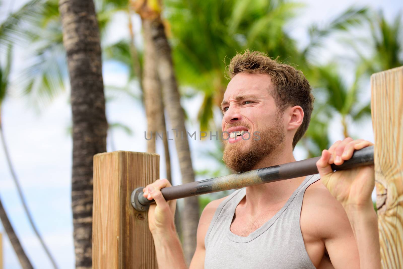 Crossfit man working out pull-ups on chin-up bar by Maridav