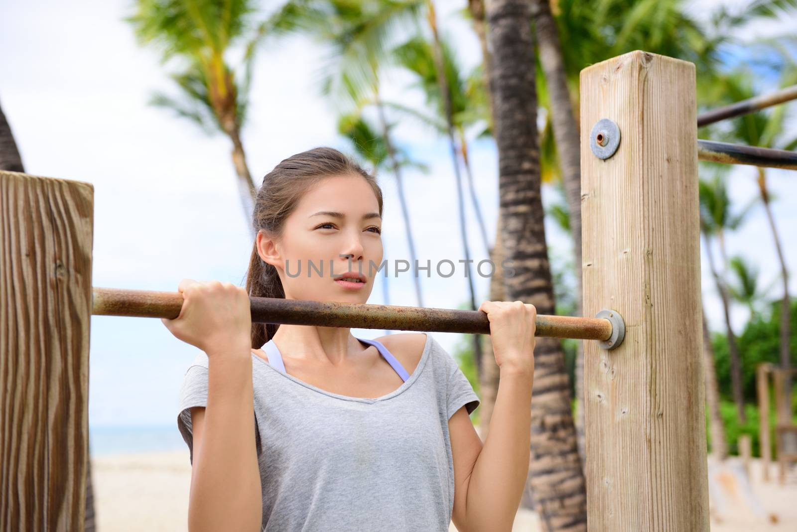 Fitness woman exercising on chin-up bar by Maridav