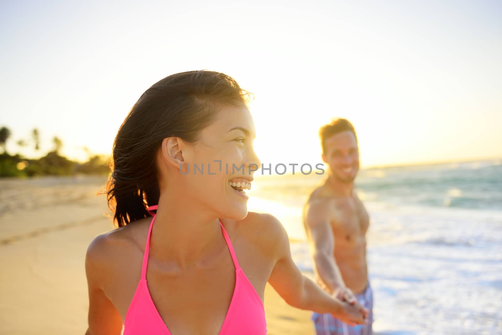 Romantic smiling young couple at beach in sunset by Maridav