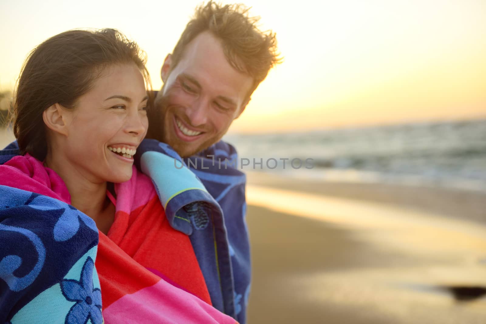 Portrait of happy romantic young interracial couple embracing each other at beach sunset having fun outdoors during holidays vacation travel. Beautiful Asian woman, handsome Caucasian man.