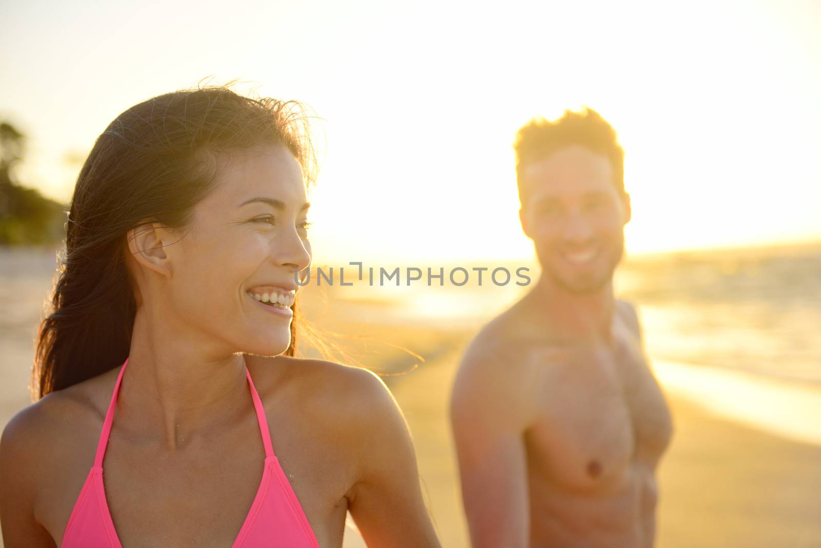 Smiling romantic young couple in beach sunset by Maridav