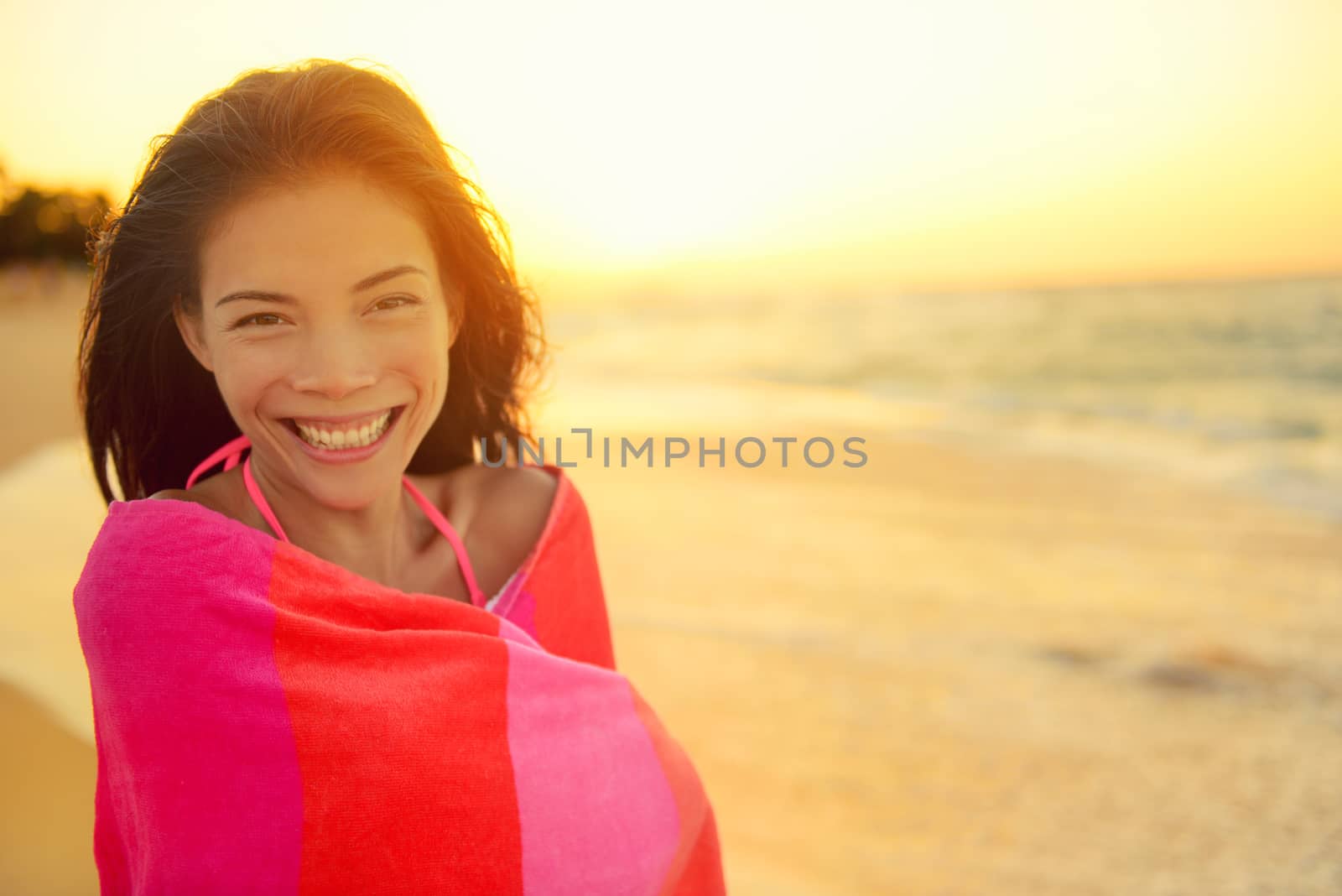 Young pretty mixed race Asian Caucasian model woman wrapped in towel standing in beach sunset. Smiling happy enjoying summer holiday travel vacation. Hawaii.