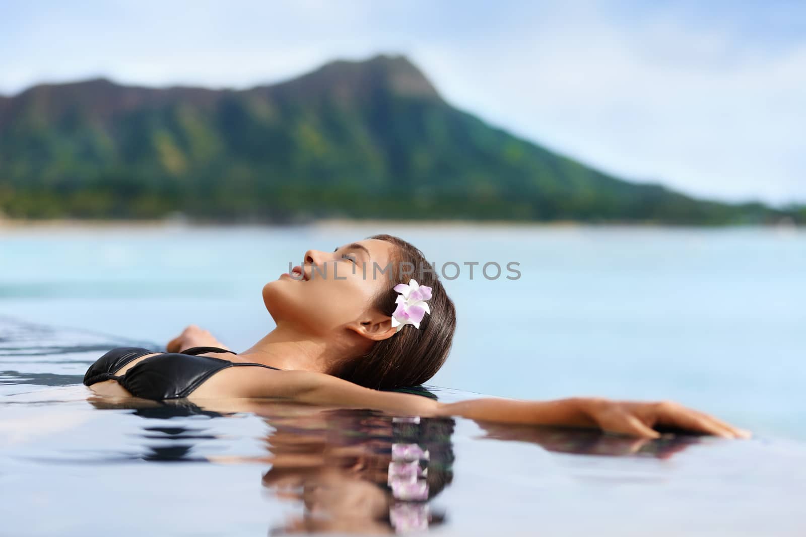 Hawaii vacation wellness pool spa woman relaxing in warm water at luxury hotel resort. Young adult at Waikiki beach in Honolulu, Oahu, Hawaii, USA.