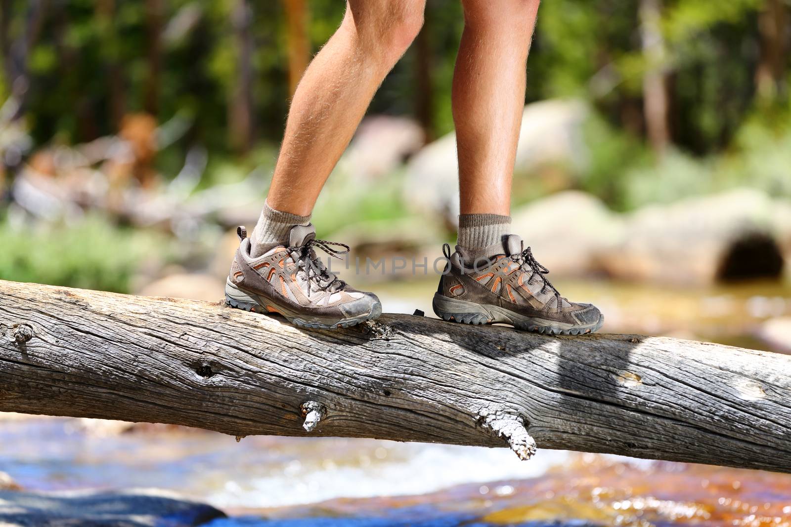 Hiking shoes - man hiker balancing crossing river by Maridav