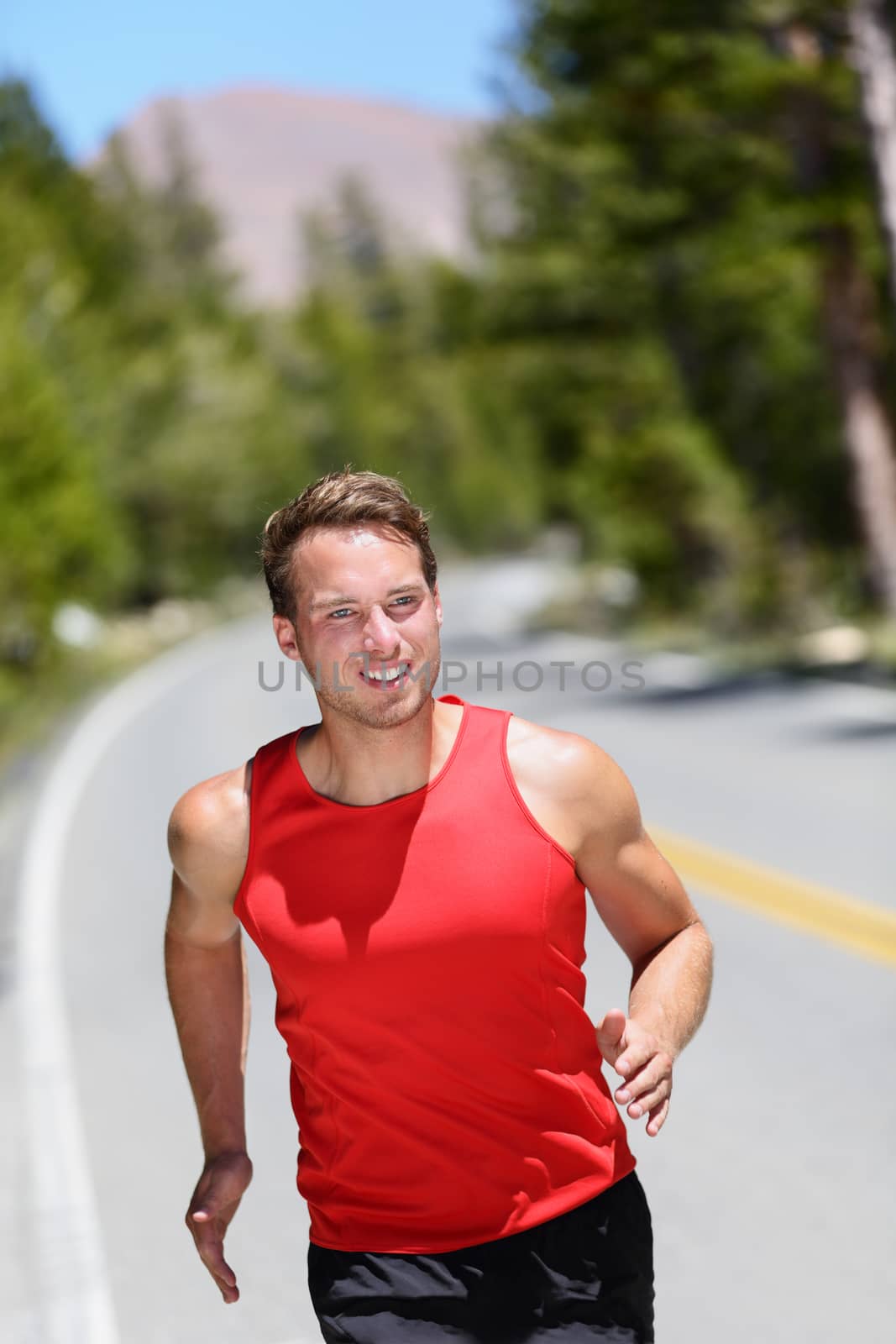 Running runner training cardio on forest road. Male athlete working out jogging in nature on a summer day. Caucasian adult.