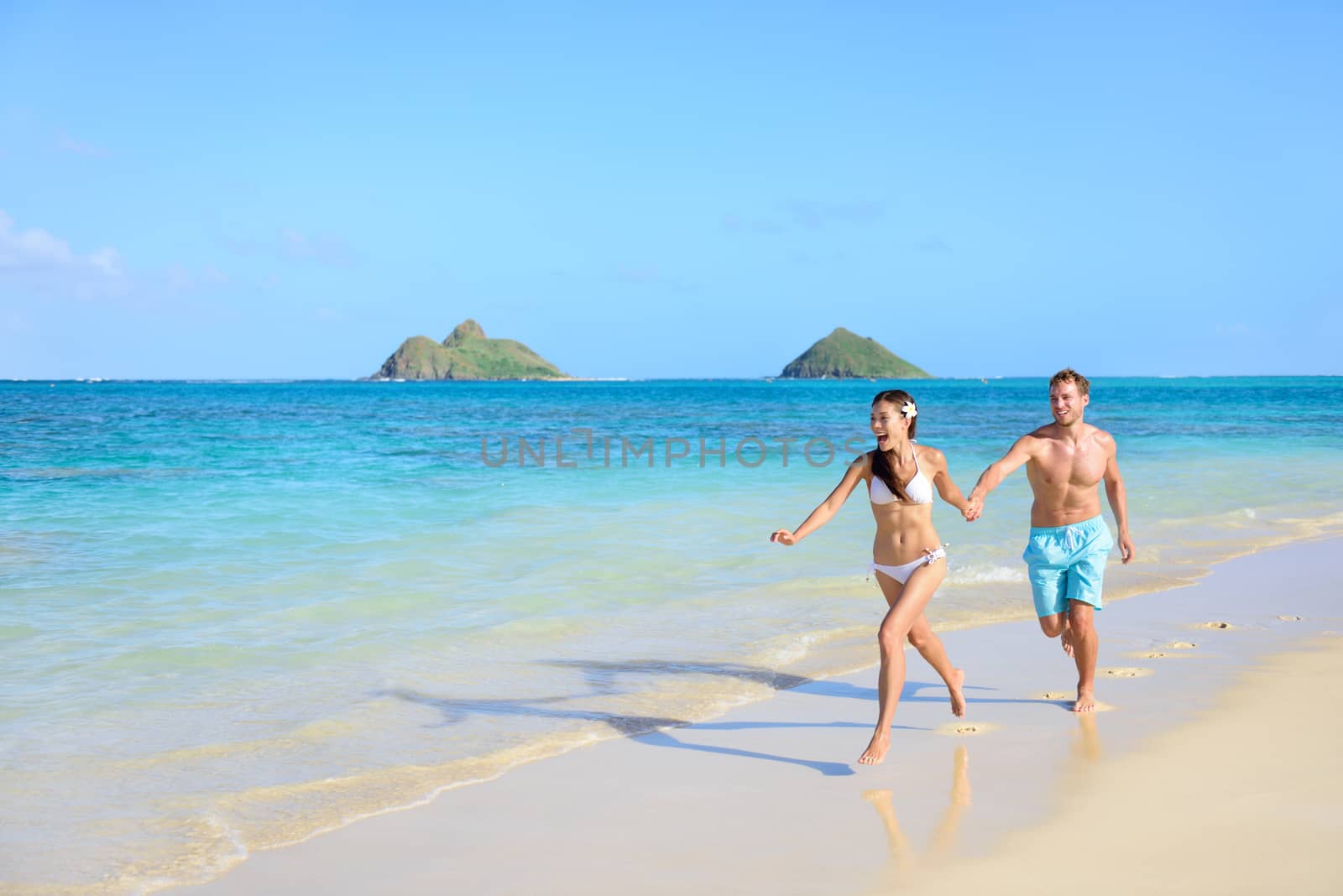 Beach travel happy vacations couple running by Maridav