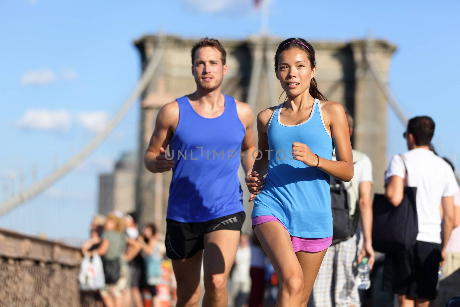 City running couple jogging outside. Runners training outdoors working out in Brooklyn with Manhattan, New York City in the background. Fit multiracial fitness couple, Asian woman, Caucasian man.