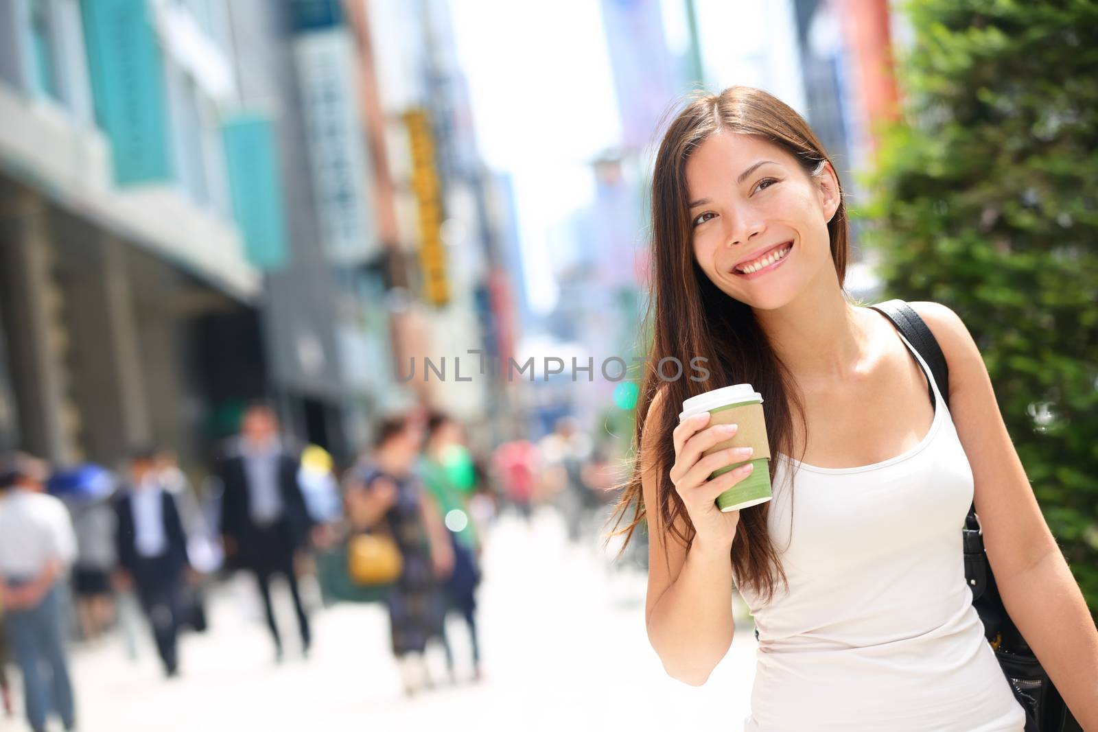 Tokyo urban woman commuter walking drinking coffee. Asian pedestrian going to work with crowd of people in the background commuting in the japanese city, Japan.