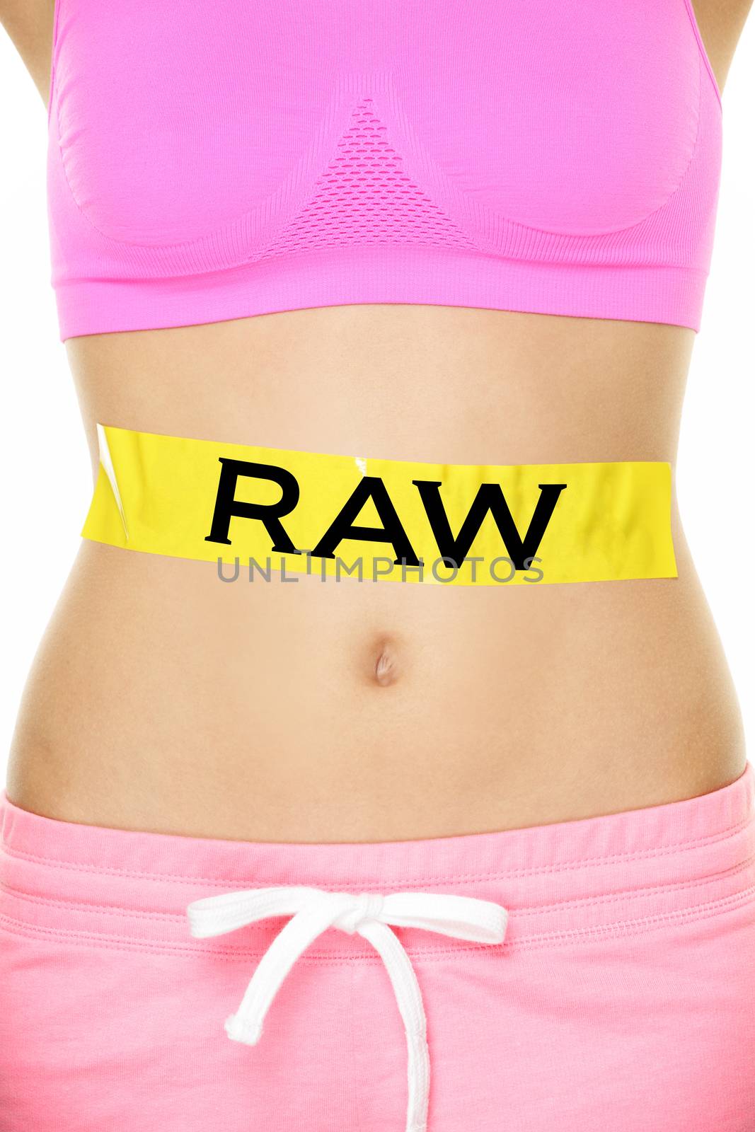 Raw food diet concept - closeup of woman's stomach eating only raw ingredients. New trend in nutrition of only uncooked or unprocessed food. Yellow label as warning or caution applied on body.