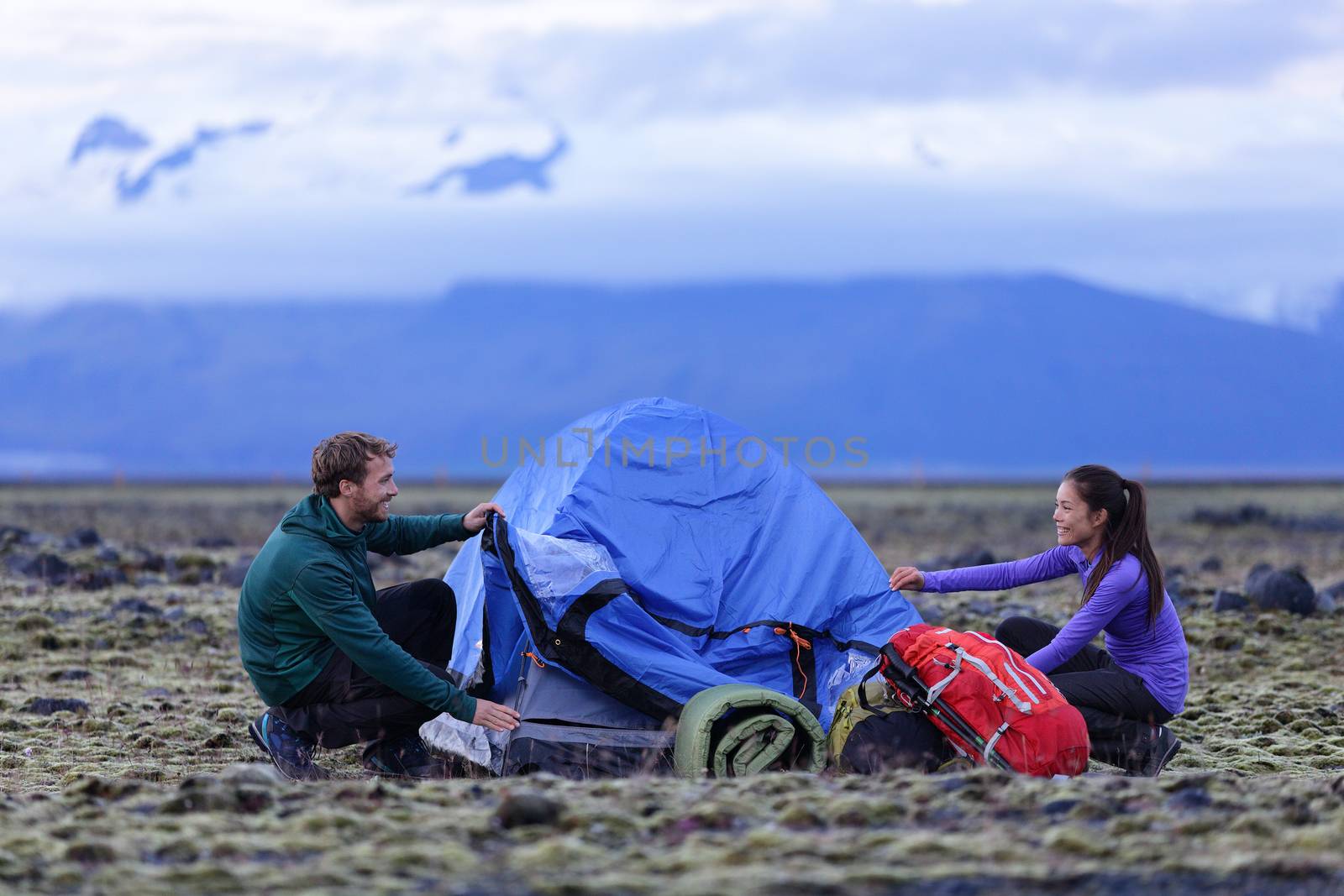 Tent - people pitching tent on Iceland at dusk by Maridav