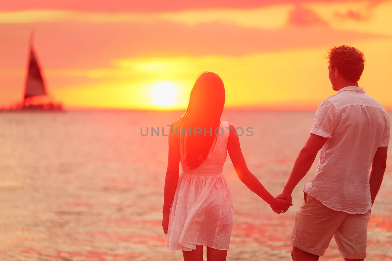 Couple holding hands together at beach sunset by Maridav