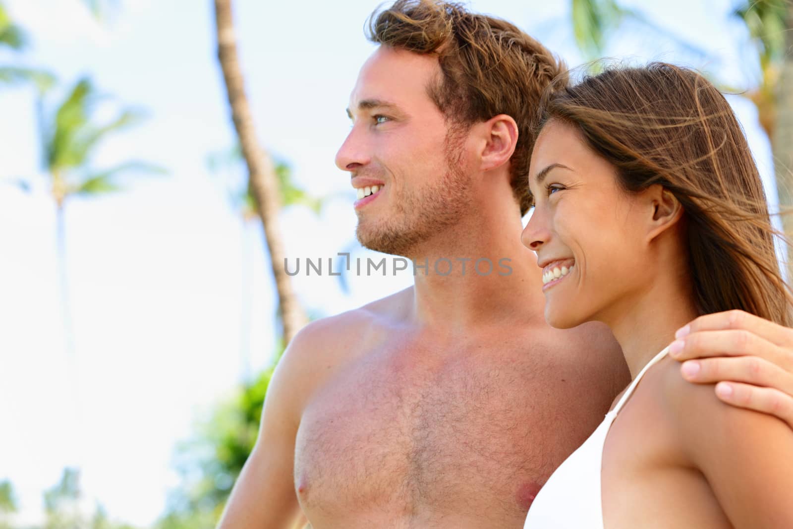 Sun tanned good looking couple at beach. Portrait of face of Asian woman and Caucasian handsome man posing for suntan concept or skincare sun protection.