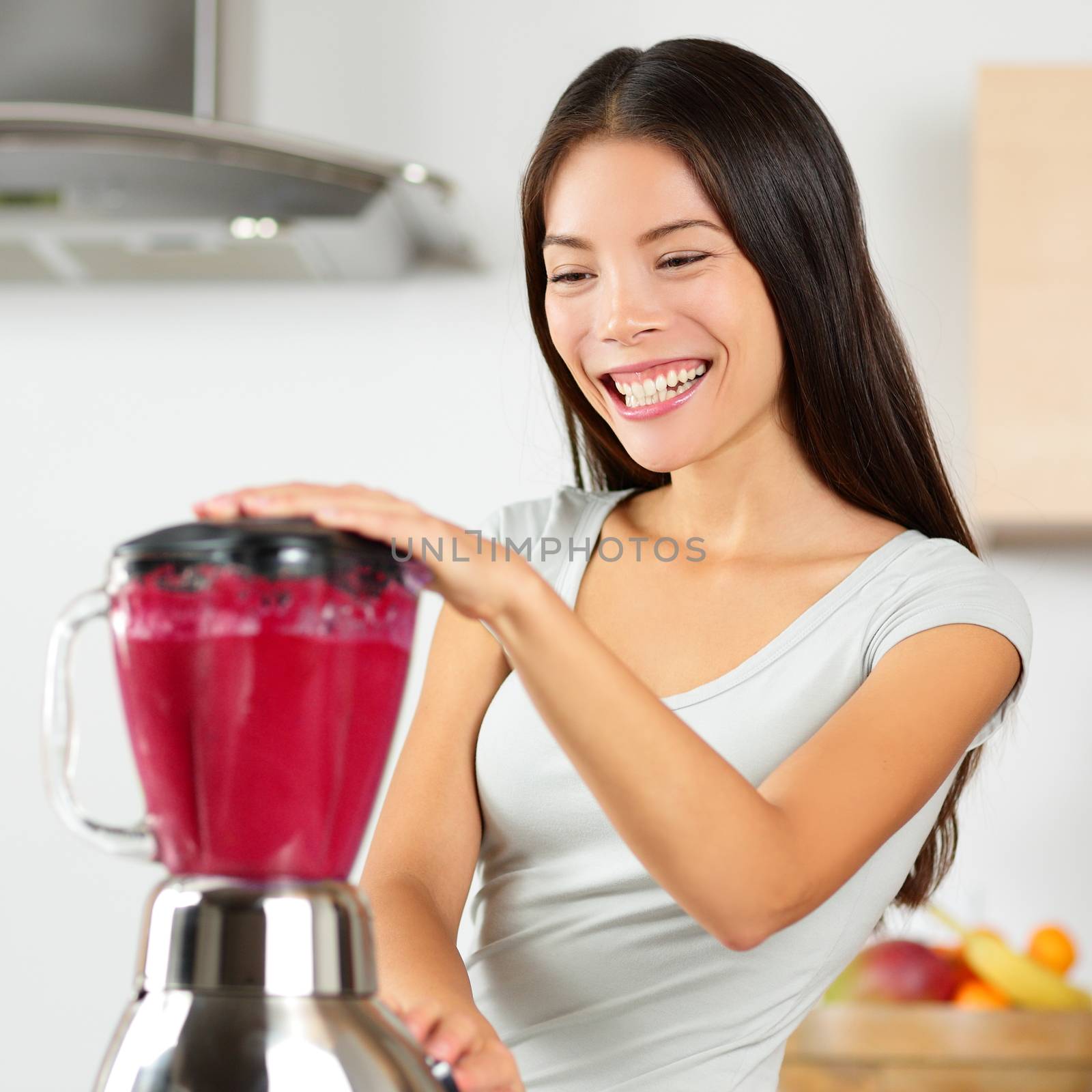 Smoothie woman blending healthy beet - fruit juice. Asian young adult using home appliance kitchen blender to make vegan organic vegetable smoothie using raw ingredients for diet.
