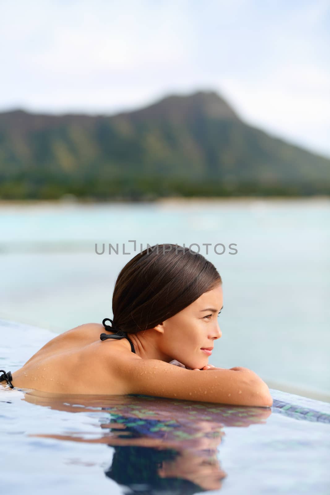 Infinity pool spa hotel resort woman relaxing at sunset overlooking Waikiki beach in Honolulu city, Oahu island, Hawaii, USA. Wellness and relaxation concept for summer vacations.