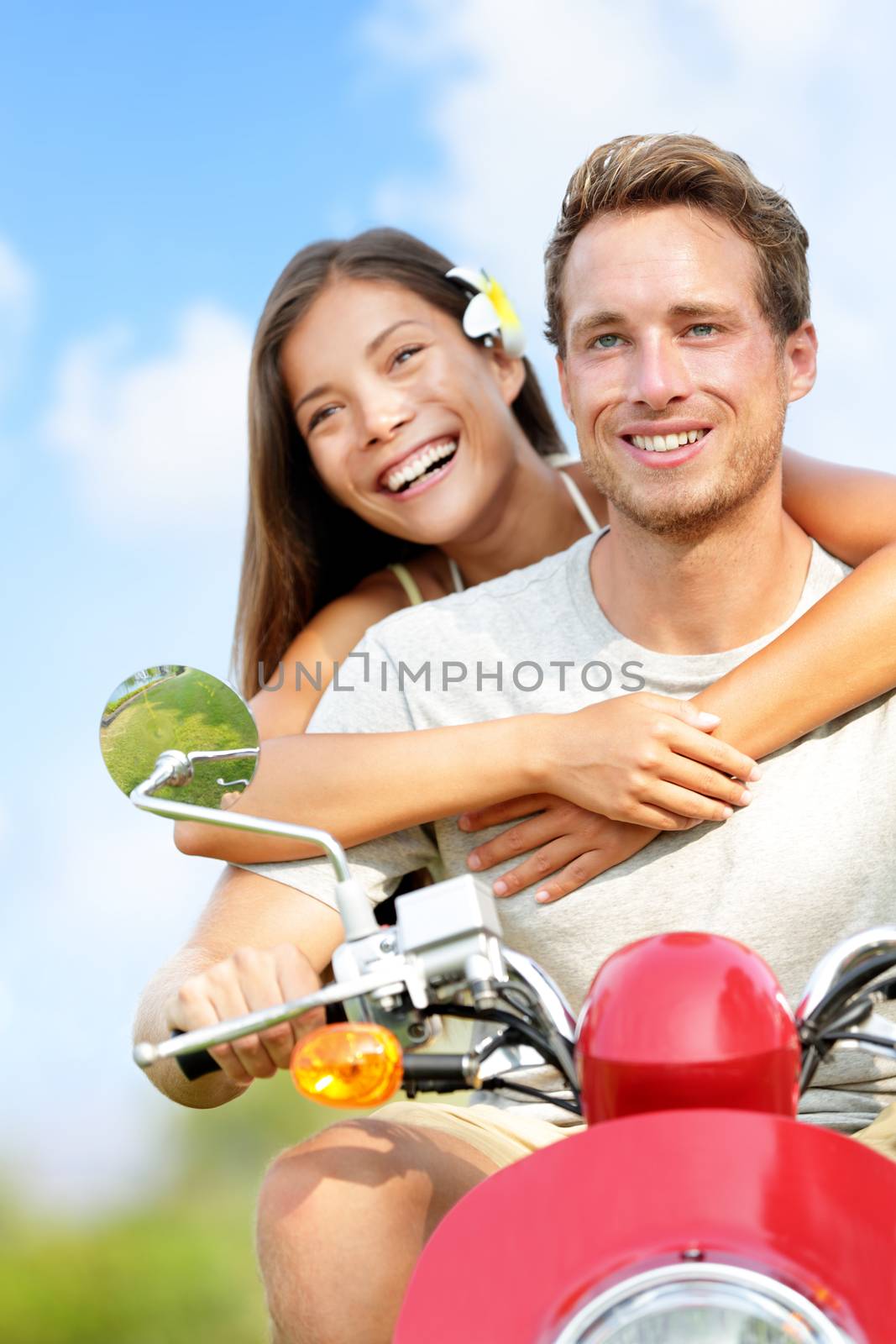 Scooter driving Happy young couple in love. Multiracial couple having fun in the free outdoor. Smiling Caucasian man and Asian woman.