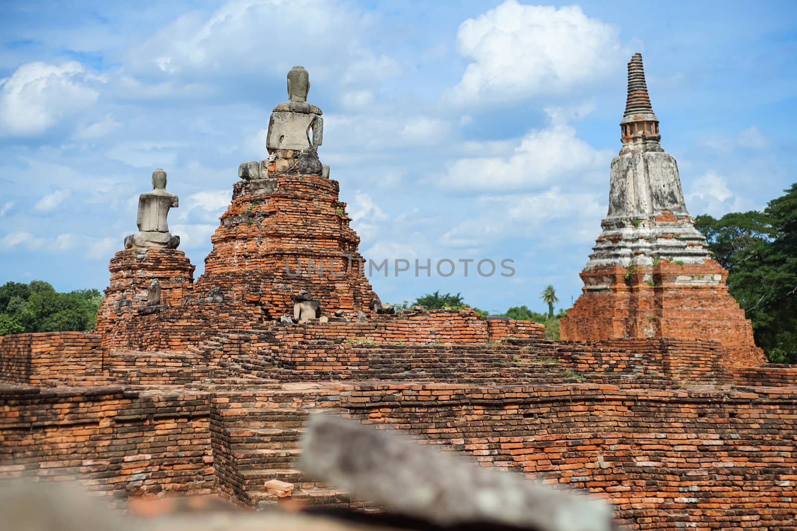 Old pagoda and ruined Buddha statue in Chaiwatthanaram temple. Ayutthaya, Thailand.