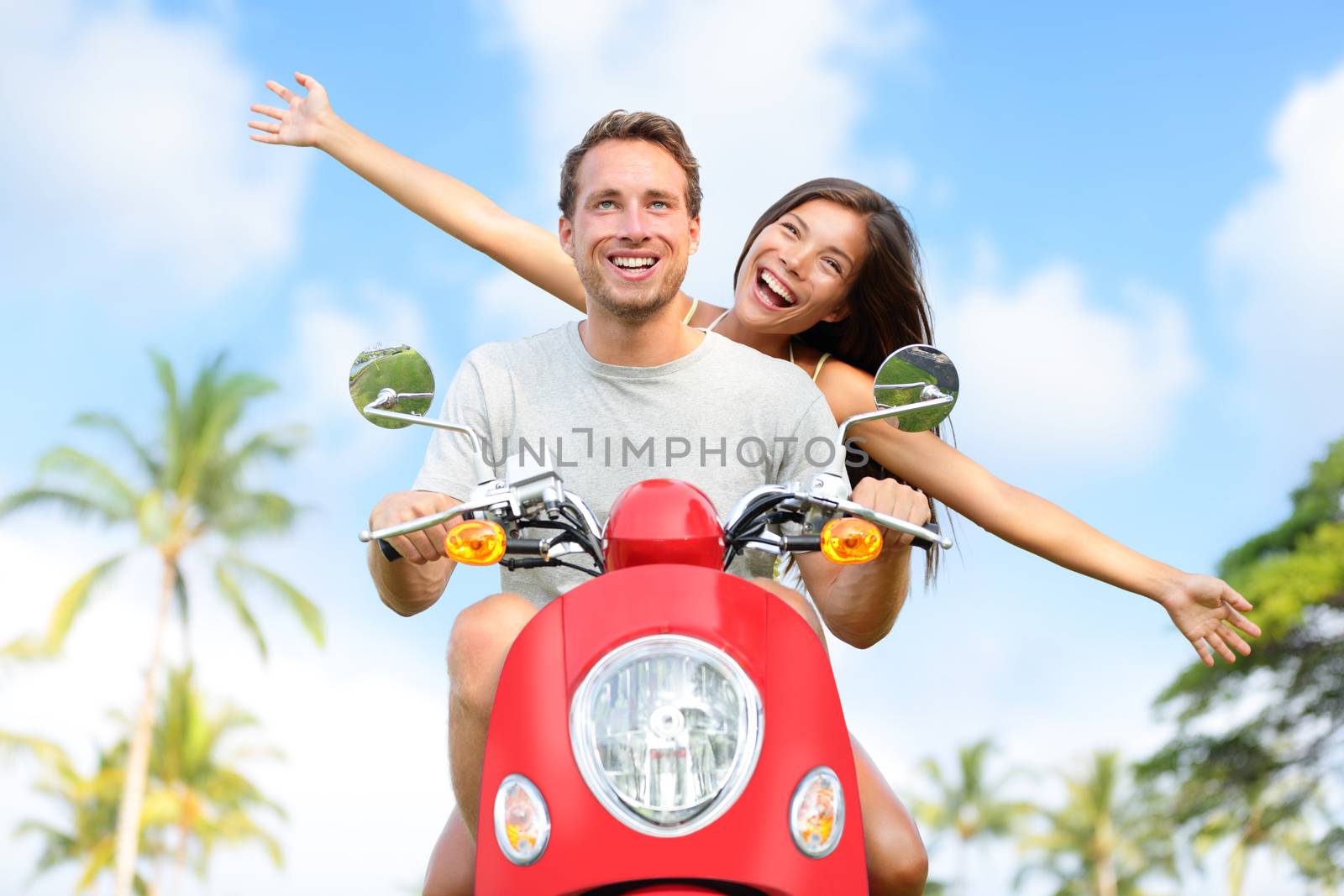 Happy free freedom couple driving scooter excited on summer holidays vacation. Young multiethnic couple in love, Asian woman, Caucasian man