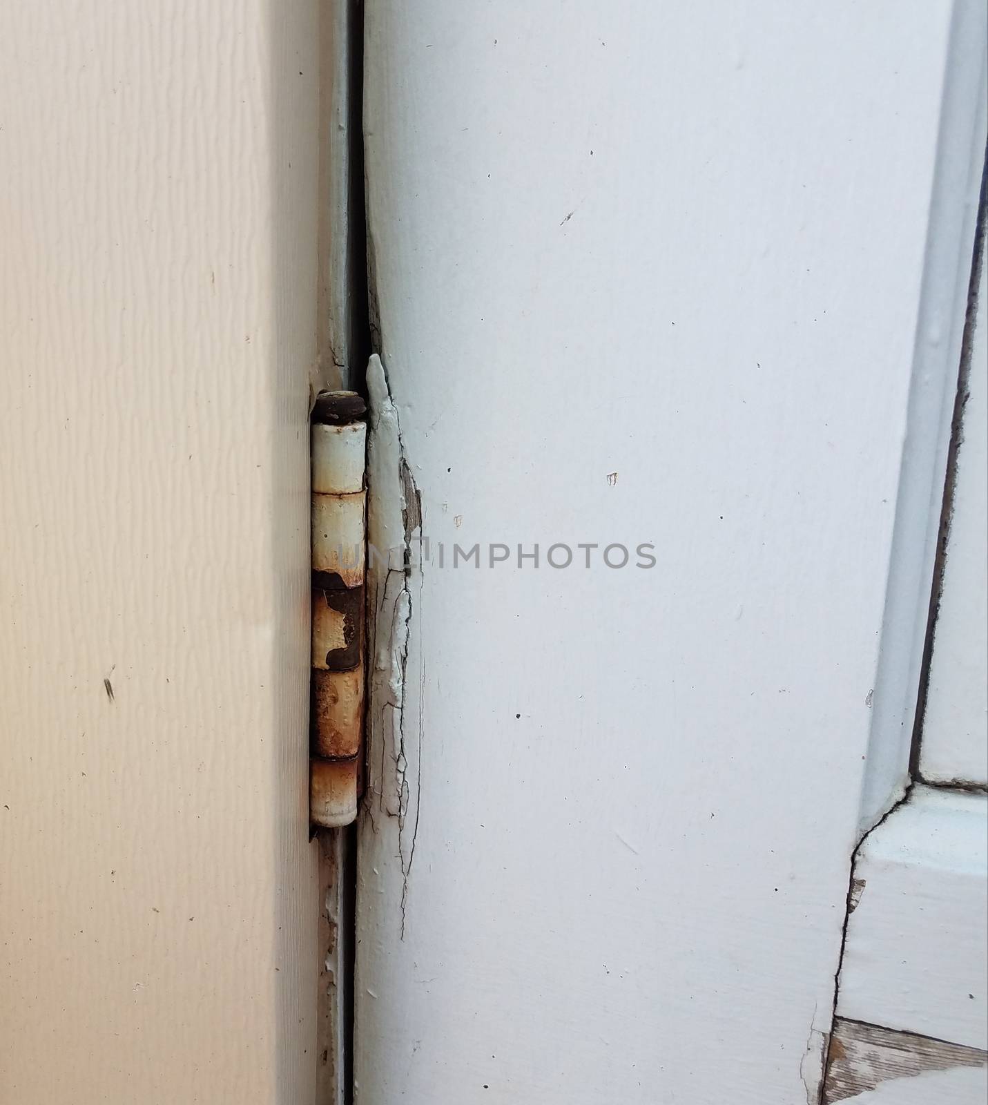 old metal hinge with rust on white wood door