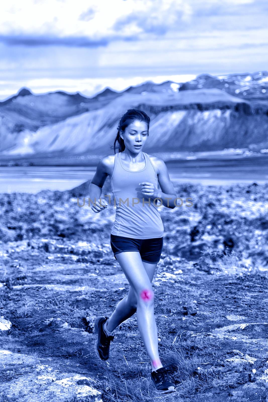 Sports woman portrait showing joints injuries. Active fitness lifestyle can cause ankle and knee sprains showed by red circles on body of female trail runner in nature. Blue monochrome filter.