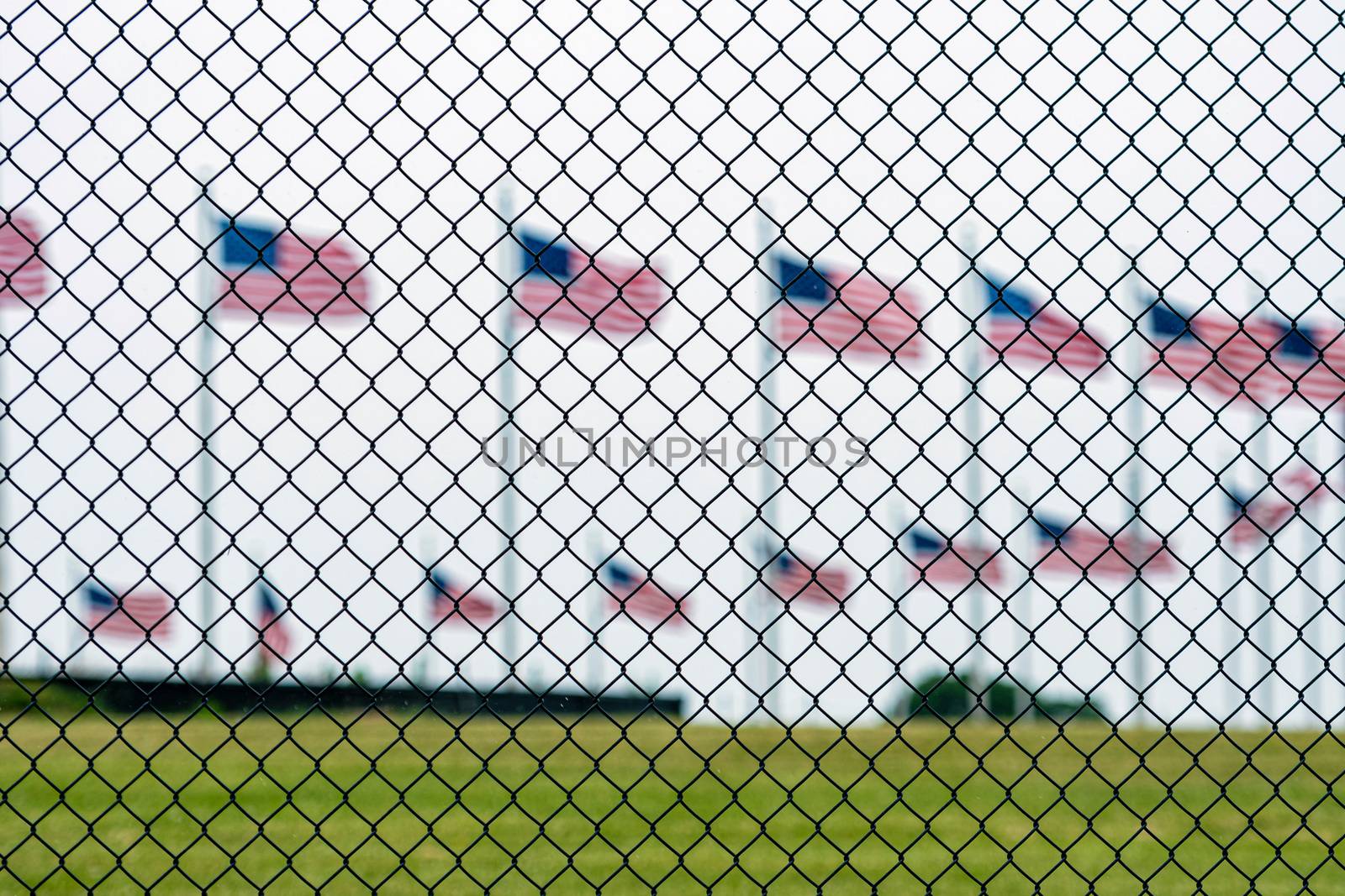 American flags at the Washington Memorial behind the wire fence. Focus on the wire fence.