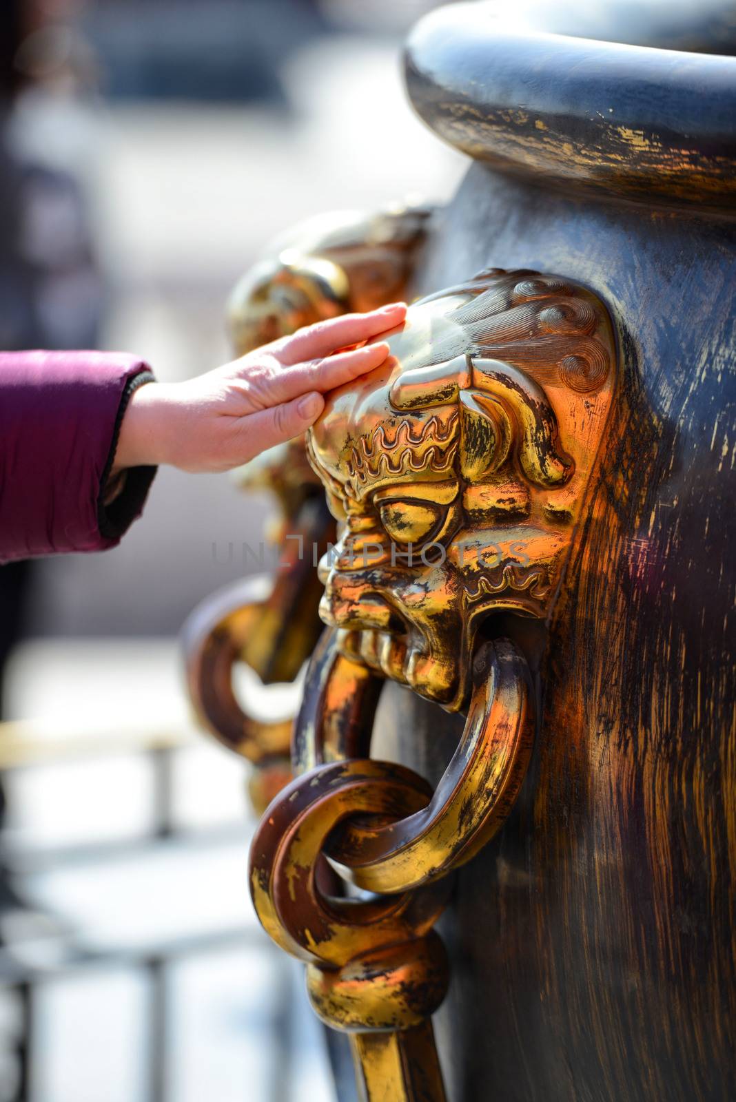 Tourists are lucky to touch the Shinning Chinese brass lion-head large-bowl handle at The Forbidden City in Beijing, China