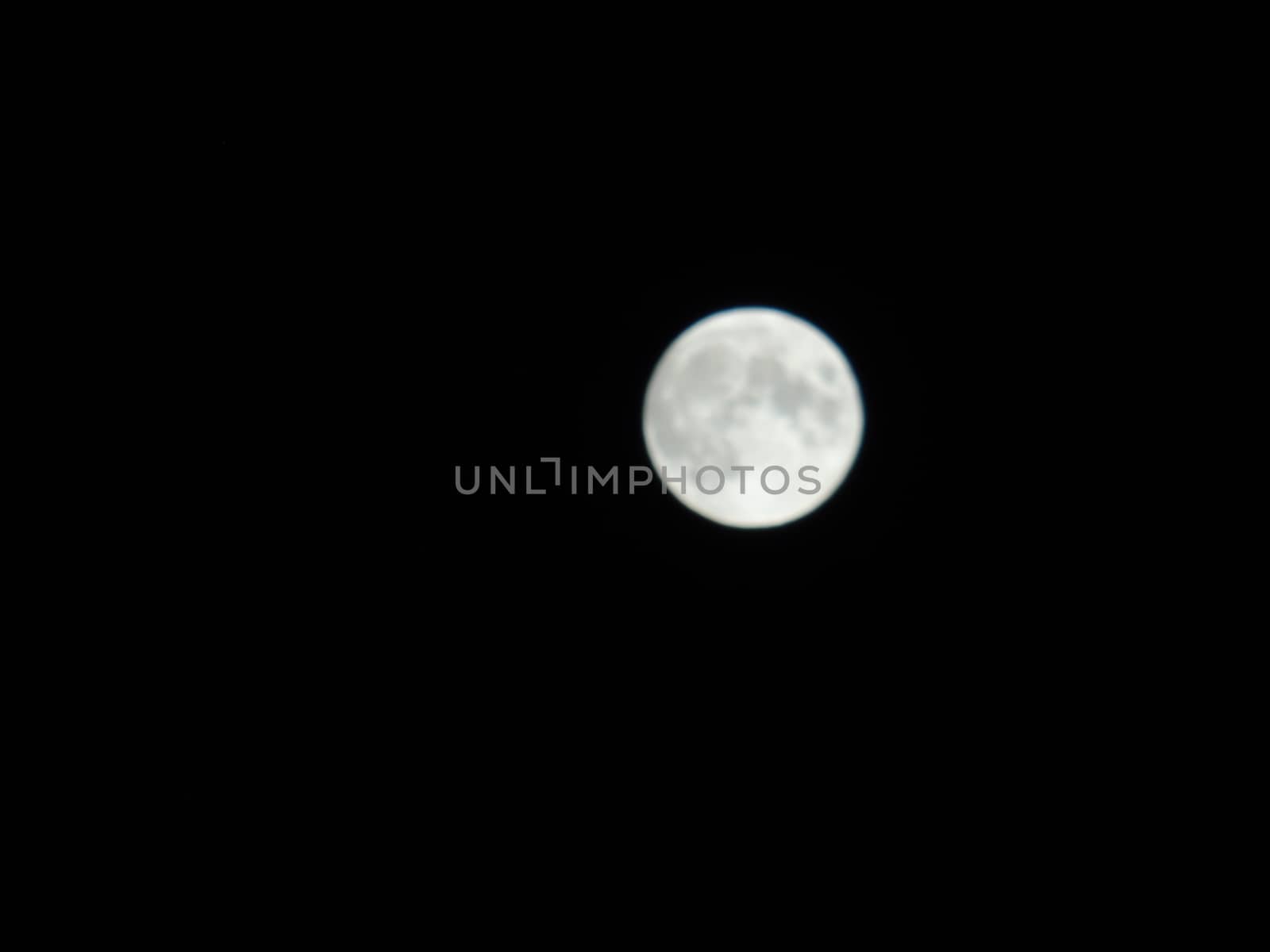 Genova, Italy - 07/05/2020: An amazing photography of the full moon over the city of Genova by night with a great clear and blue sky in the background and some stars.