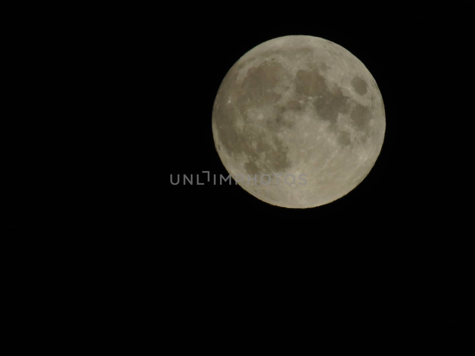 Genova, Italy - 07/05/2020: An amazing photography of the full moon over the city of Genova by night with a great clear and blue sky in the background and some stars.