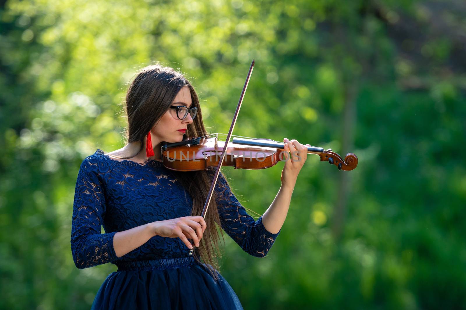 Young woman playing the violin at park. Shallow depth of field.