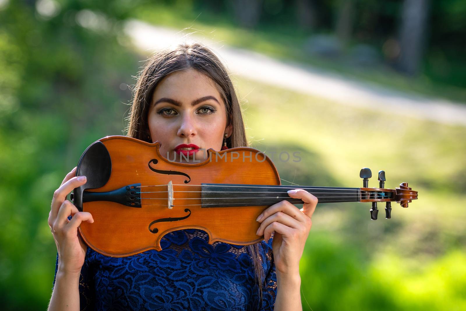 Portrait of a positive young woman. Part of the face is covered by the neck of the violin.