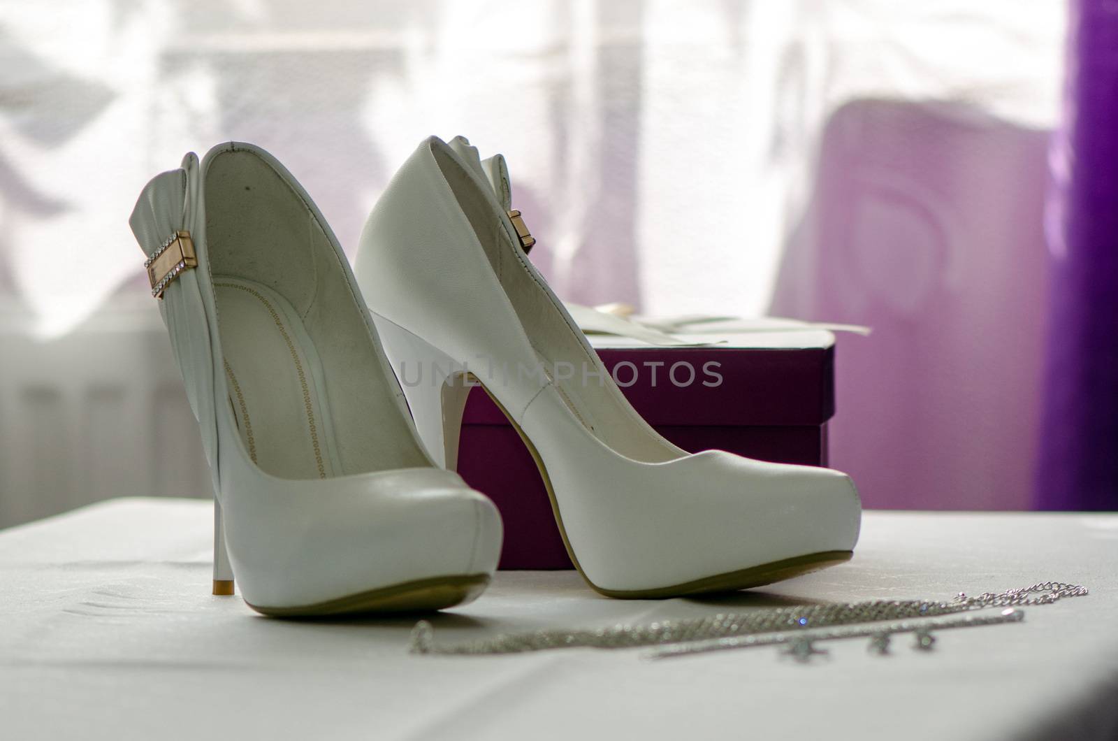 Standing on a white tablecloth white bridal shoes. by askoldsb