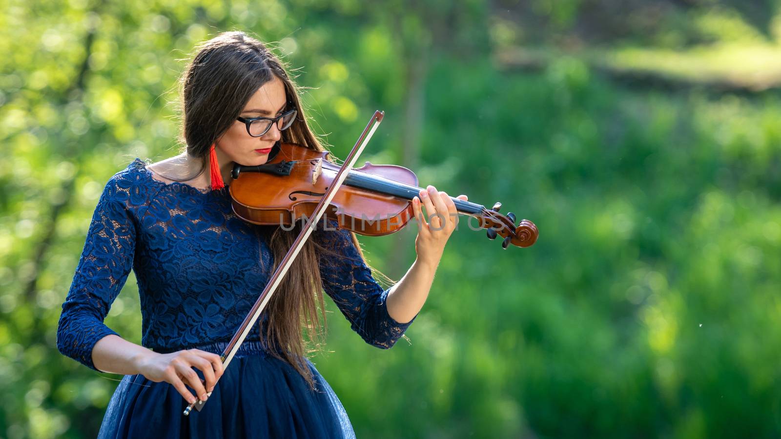 Young woman playing the violin at park. Shallow depth of field.