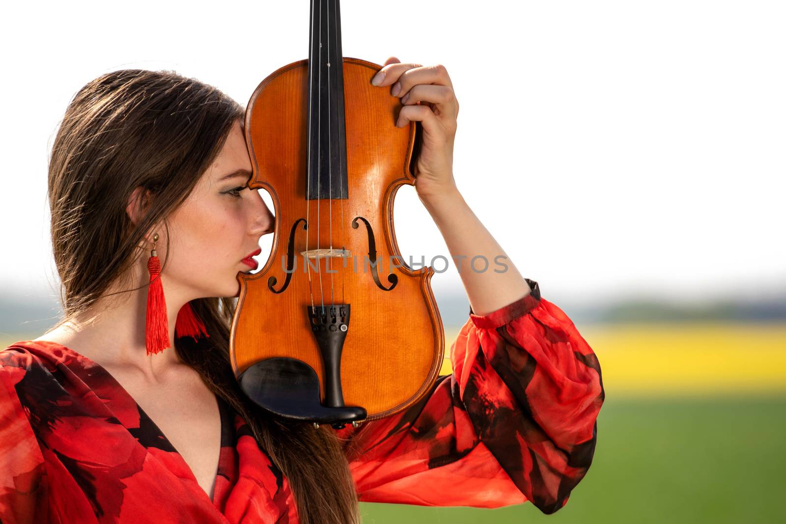 Portrait of a positive young woman. Part of the face is covered by the neck of the violin.