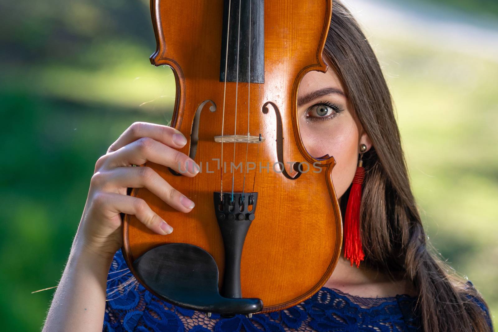 Portrait of a positive young woman. Part of the face is covered by the neck of the violin.