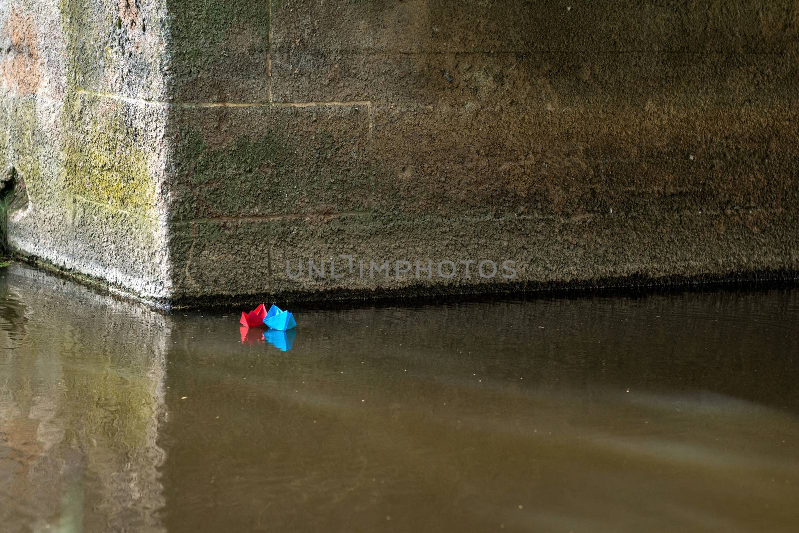 Red and blue paper boat is flying on the river. Wedding concept.