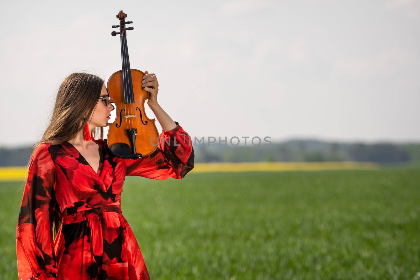 Portrait of a positive young woman. Part of the face is covered by the neck of the violin.