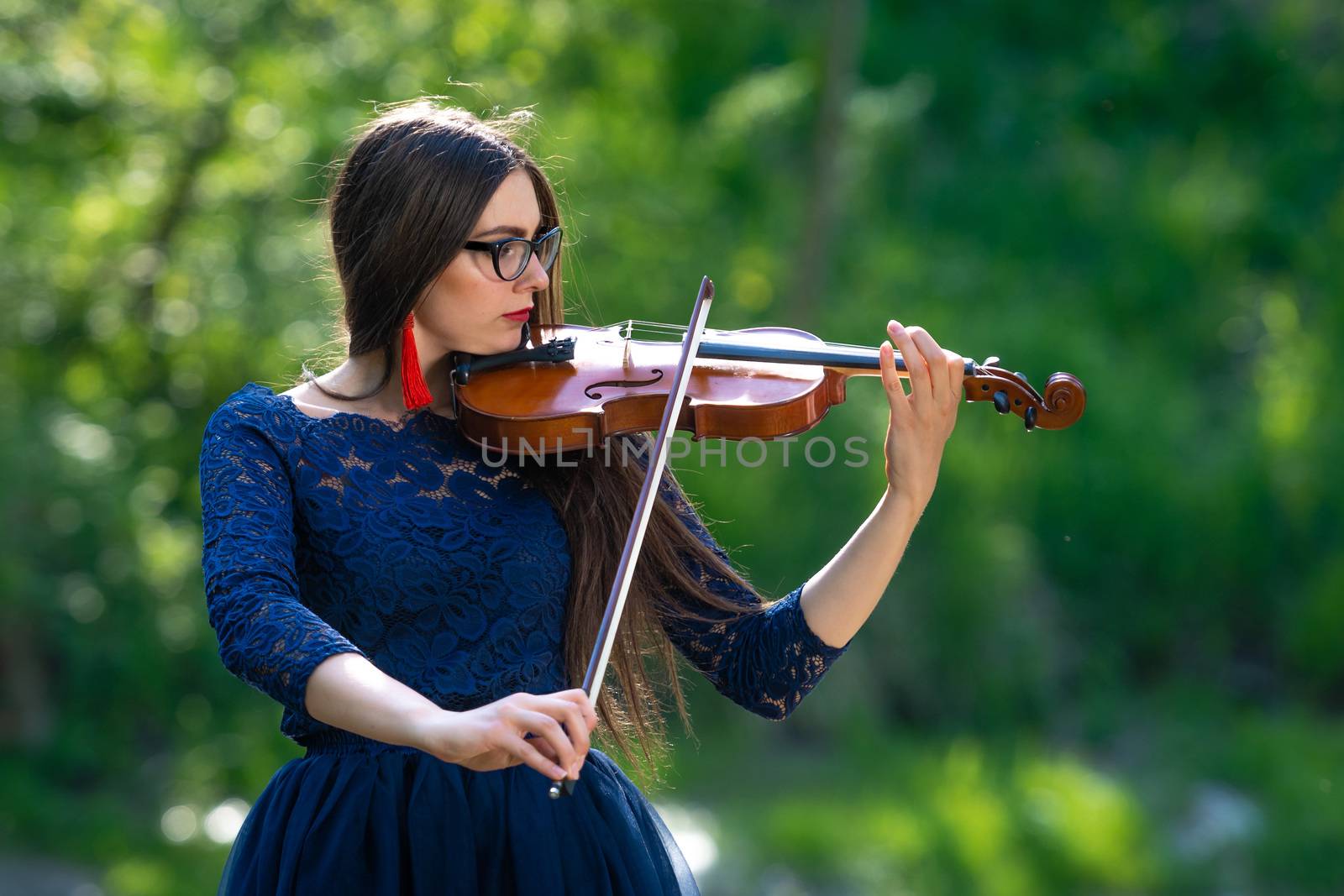 Young woman playing the violin at park. Shallow depth of field.