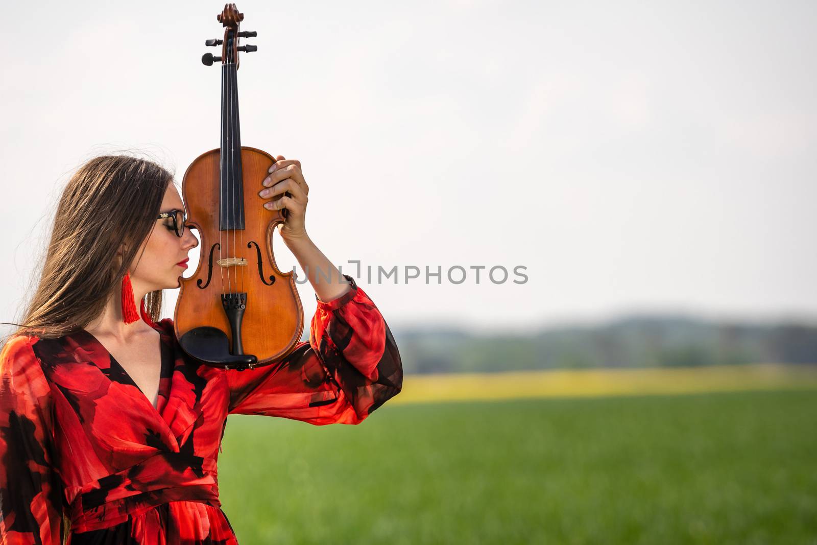 Portrait of a positive young woman. Part of the face is covered by the neck of the violin.