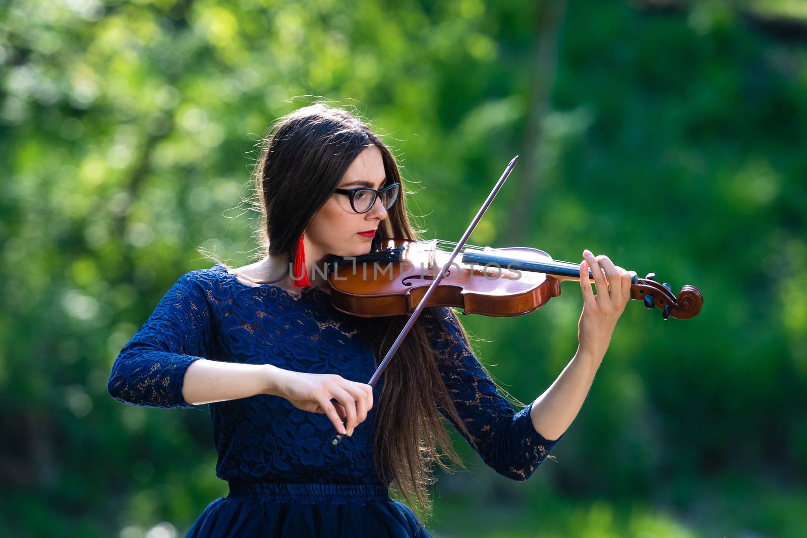 Young woman playing the violin at park. Shallow depth of field.