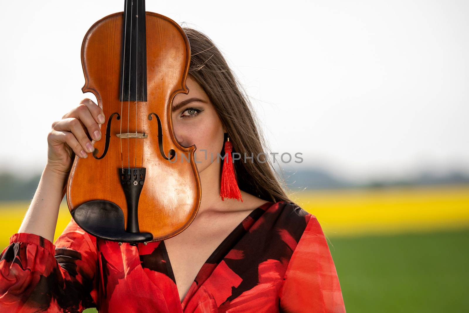 Portrait of a positive young woman. Part of the face is covered by the neck of the violin.