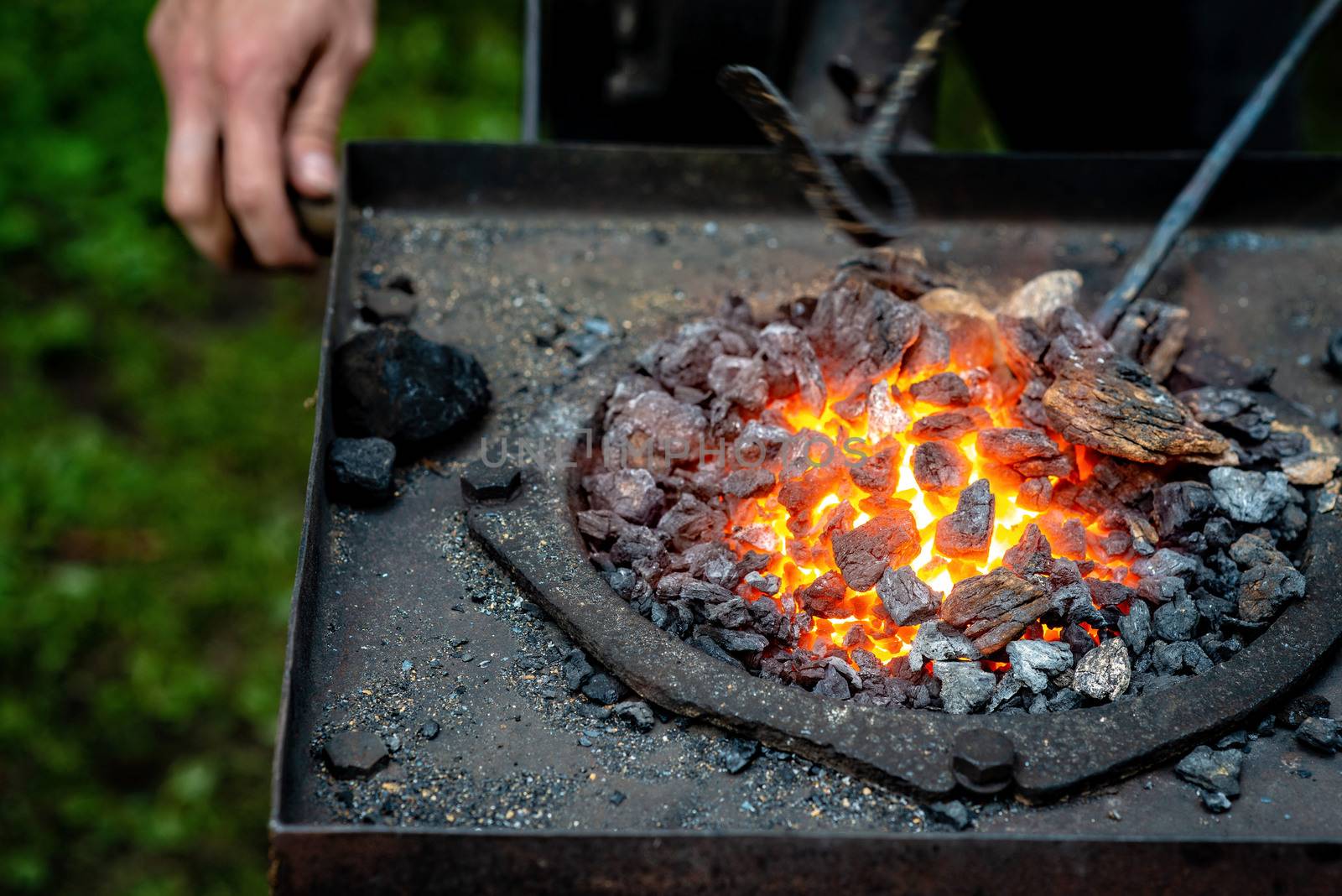 Hot item is inserted into the blacksmith's forge from which the tongues of flame. Concept: blacksmithing, forge - Image