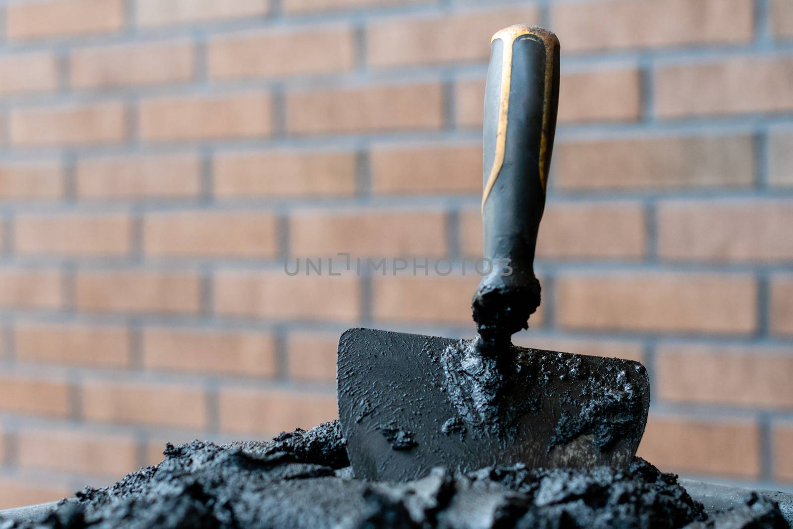 Bricklayers trowel in fresh mortar with bricks wall n the background.