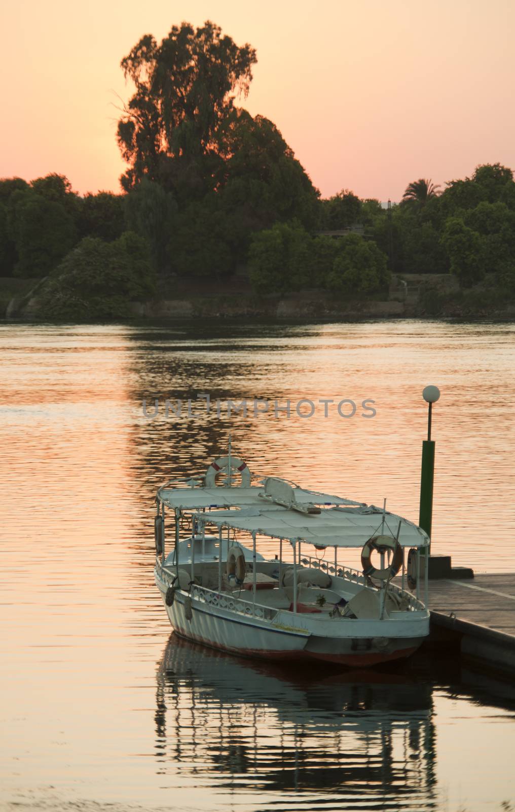 Small wooden boat moored at a jetty on river in the sunset
