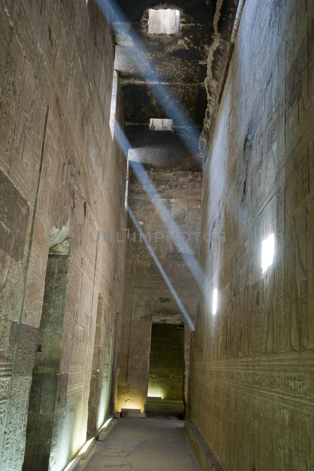 Beams of sunlight across a corridor inside an ancient egyptian temple with hieroglyphic carvings