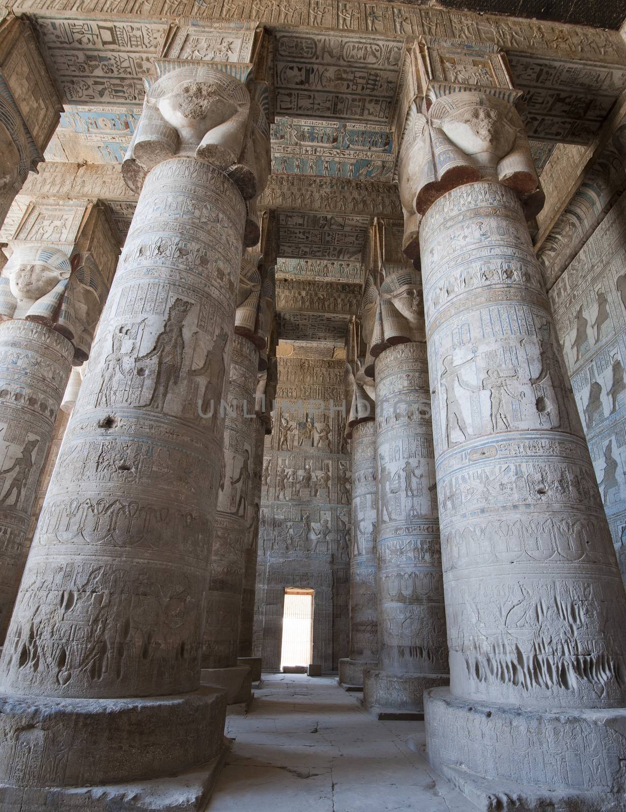 Columns inside an ancient egyptian temple covered in hieroglyphic carvings and paintings