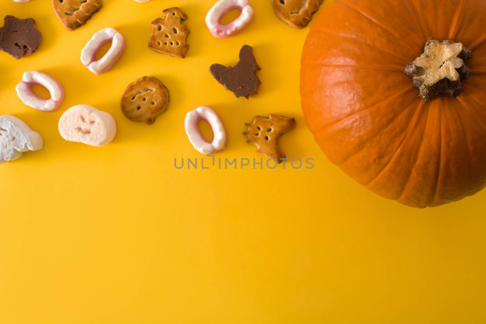 Halloween cookies and Halloween pumpkin on yellow background.