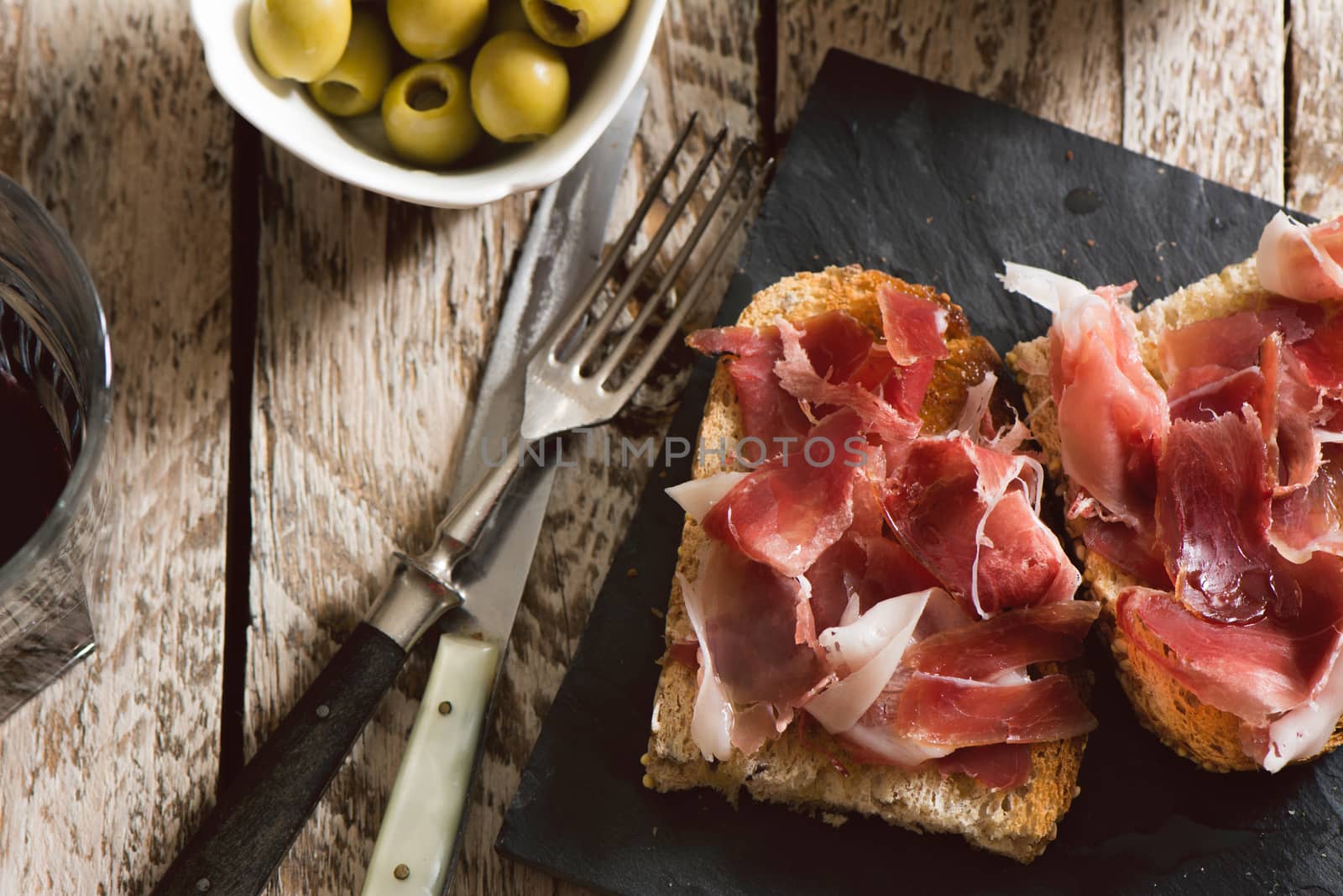 Delicious appetizer of spanish ham and salad, on rustic table